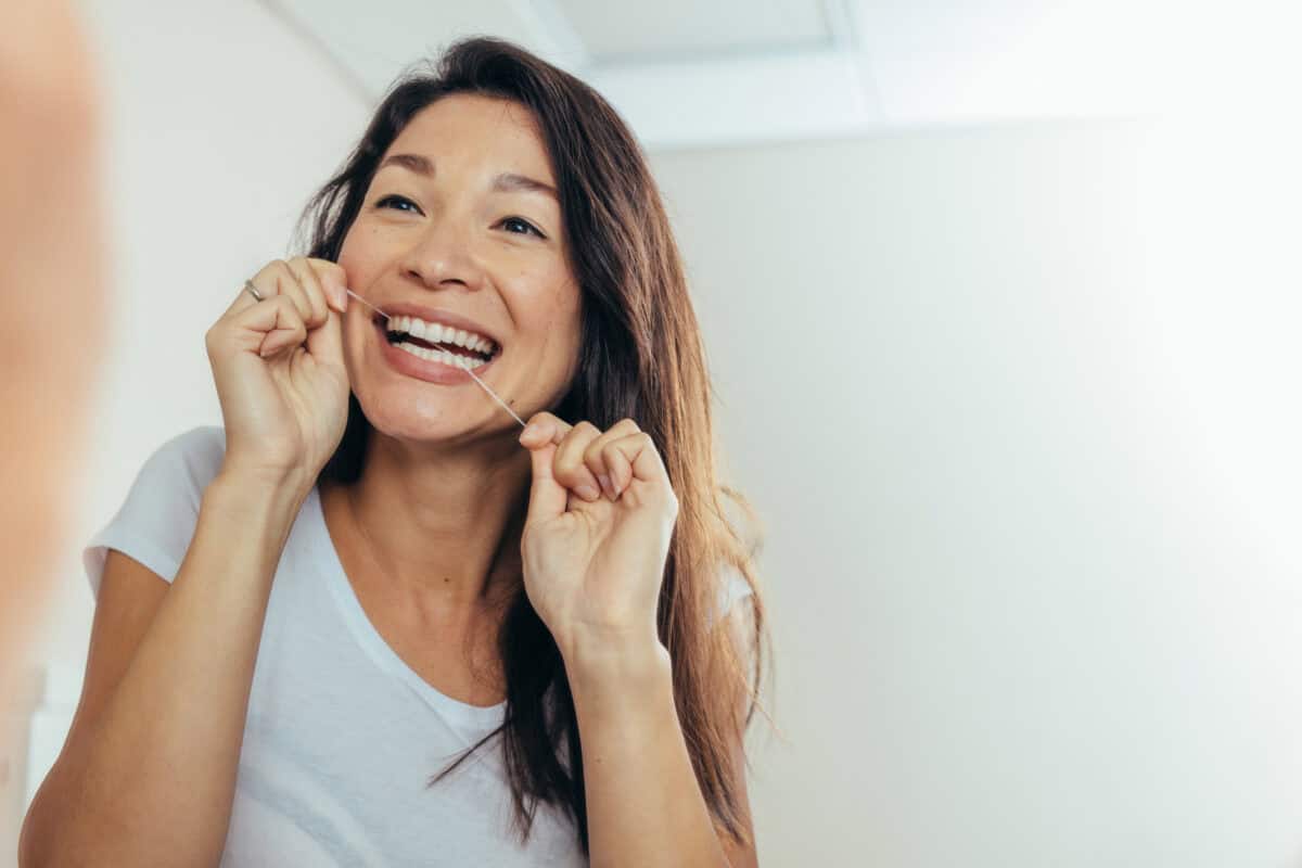 woman looking in the mirror, flossing. floss like a boss.