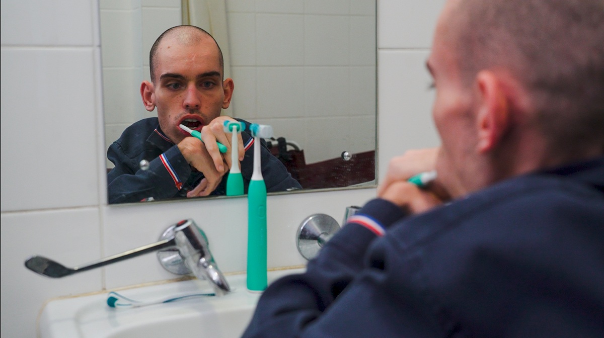 Young man brushing teeth in bathroom, focusing on oral hygiene routine.