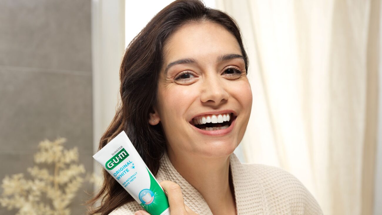 Woman holding toothpaste in bathrobe.